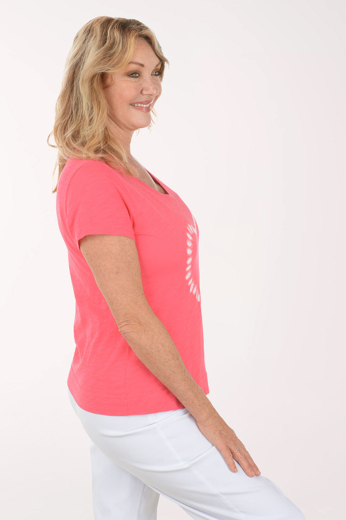 A woman wearing a short sleeve pink top with a heart print.