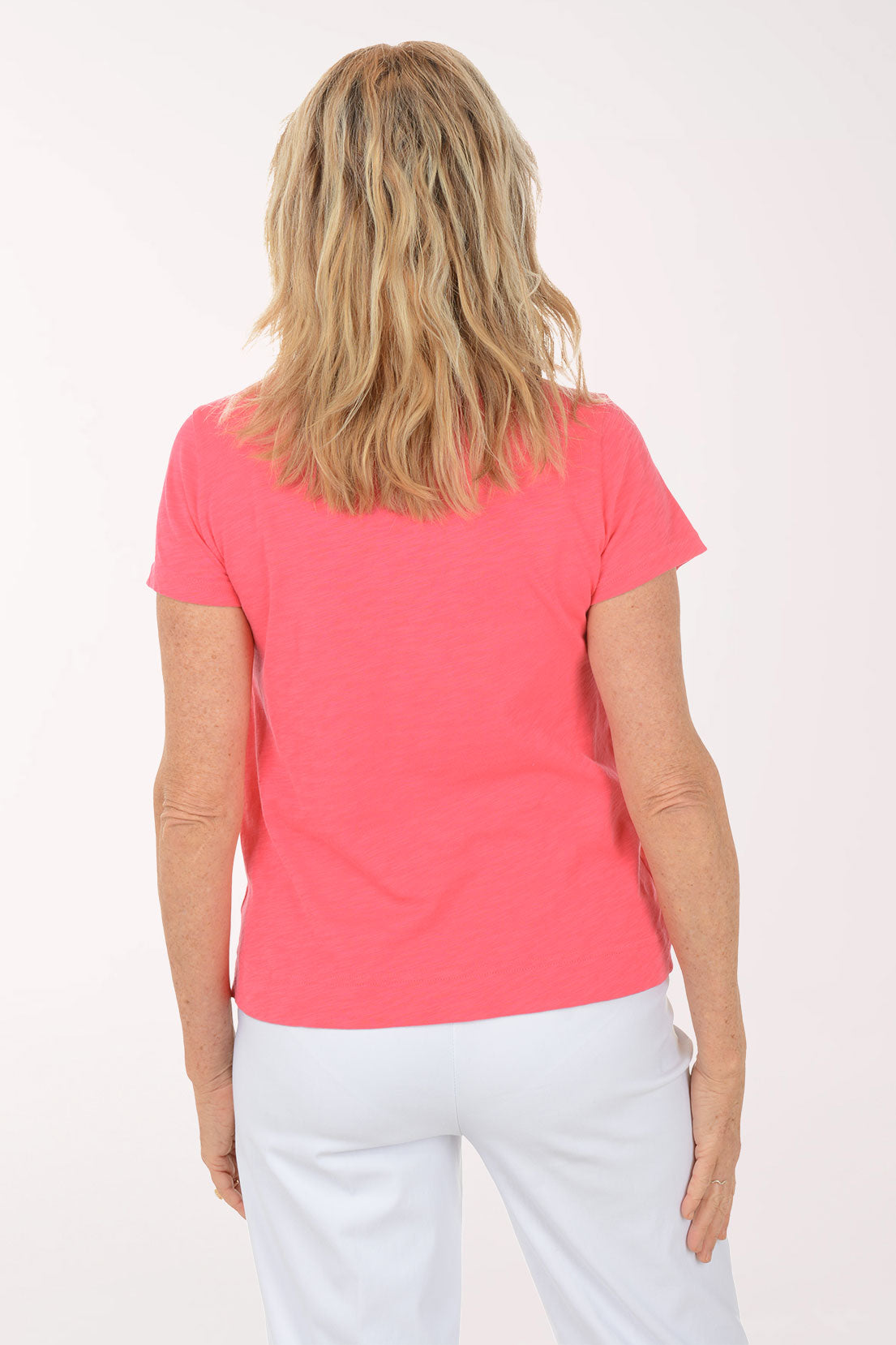 A woman wearing a short sleeve pink top with a heart print.