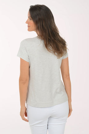 A woman wearing a short sleeve grey top.