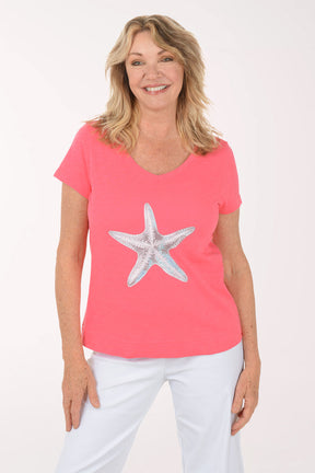 A woman wearing a short sleeve coral top.