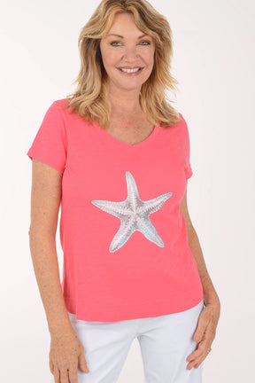 A woman wearing a short sleeve coral top.