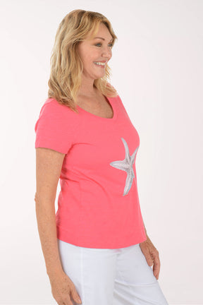 A woman wearing a short sleeve coral top.