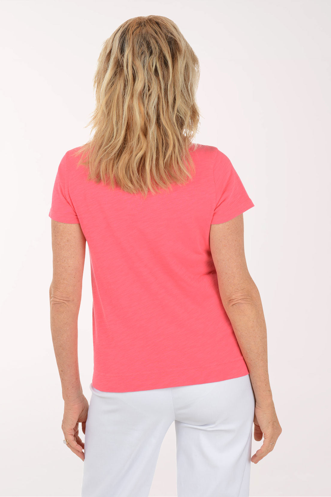 A woman wearing a short sleeve coral top.