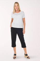 Woman wearing a white and black striped top and black capri pants on a white background