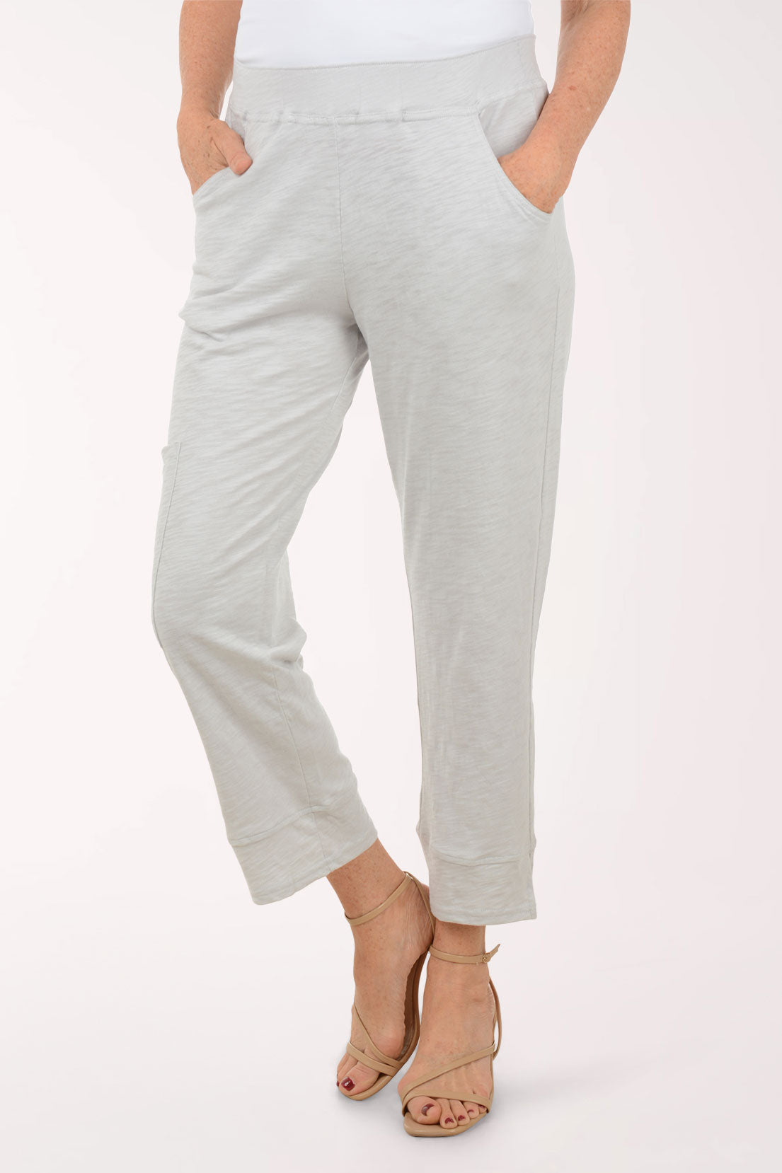 A woman wearing light grey capri pants.