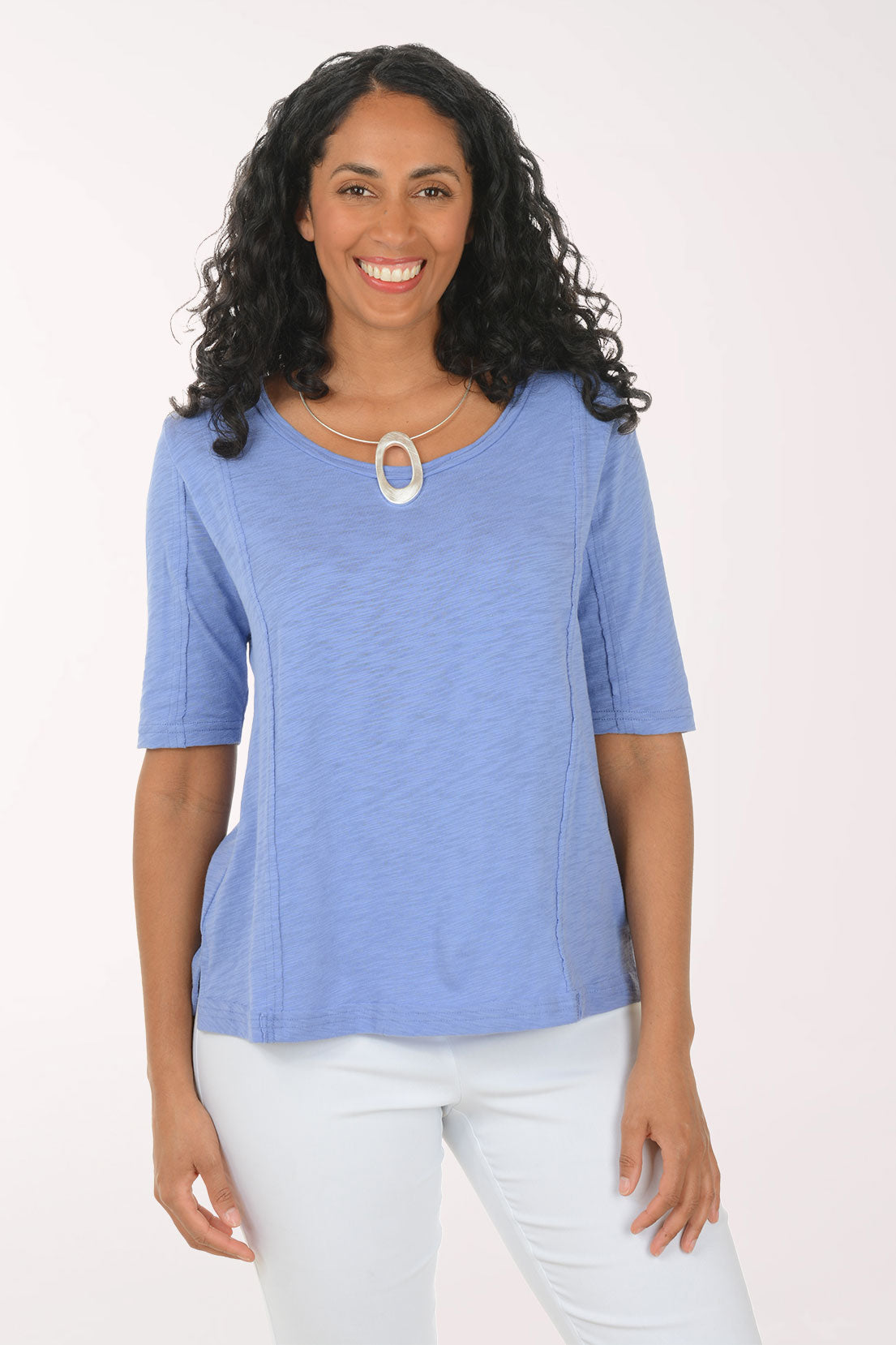 Woman wearing a blue top and white pants on a white background