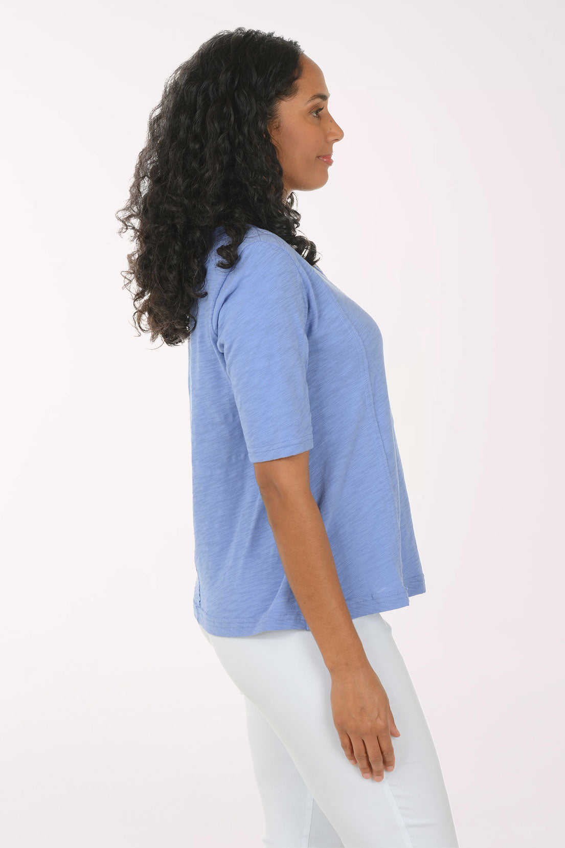Woman wearing a blue top and white pants on a white background