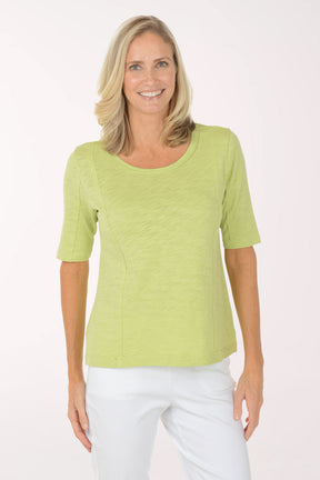 Woman wearing a green top and white pants on a white background