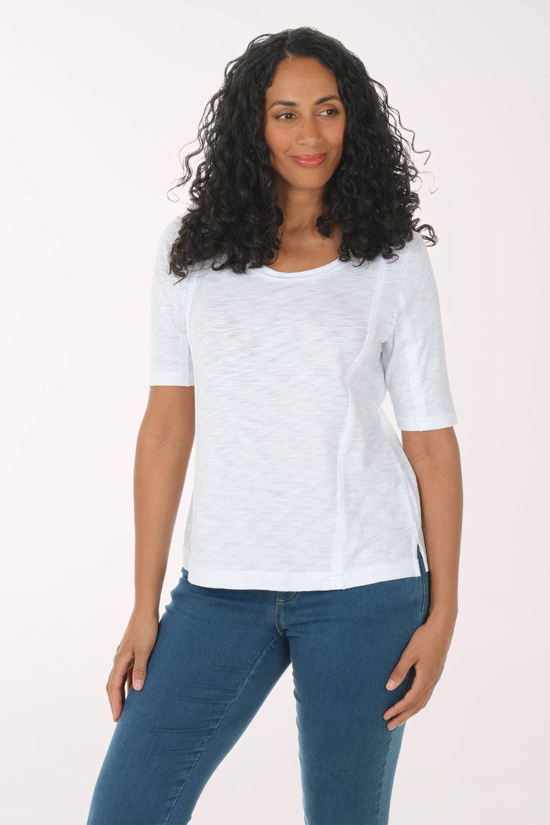 Woman wearing a white t-shirt and blue jeans on a plain background