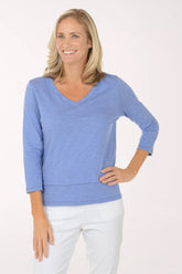 Woman wearing a blue sweater and white pants on a white background