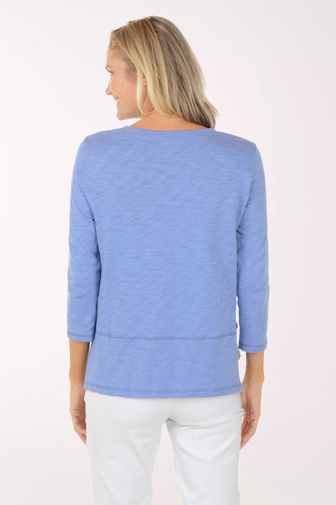 Woman wearing a blue sweater and white pants on a white background