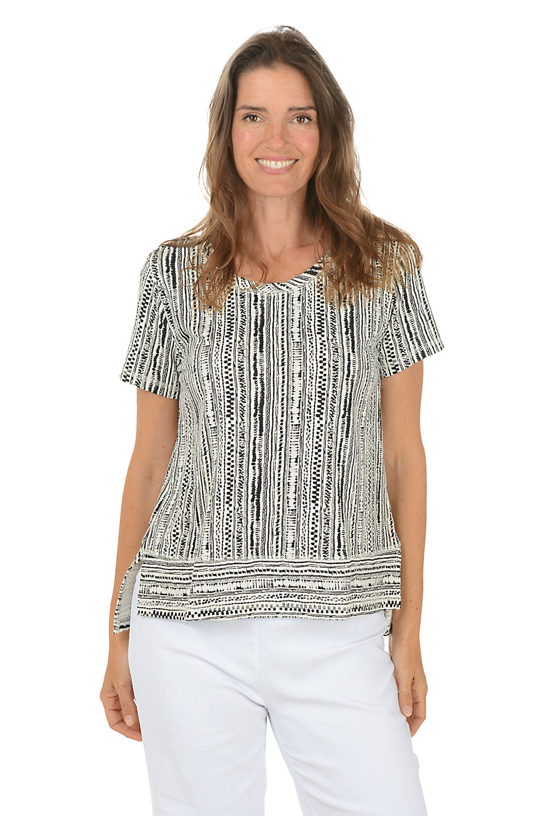 Woman wearing a patterned black and white top with white pants on a white background.
