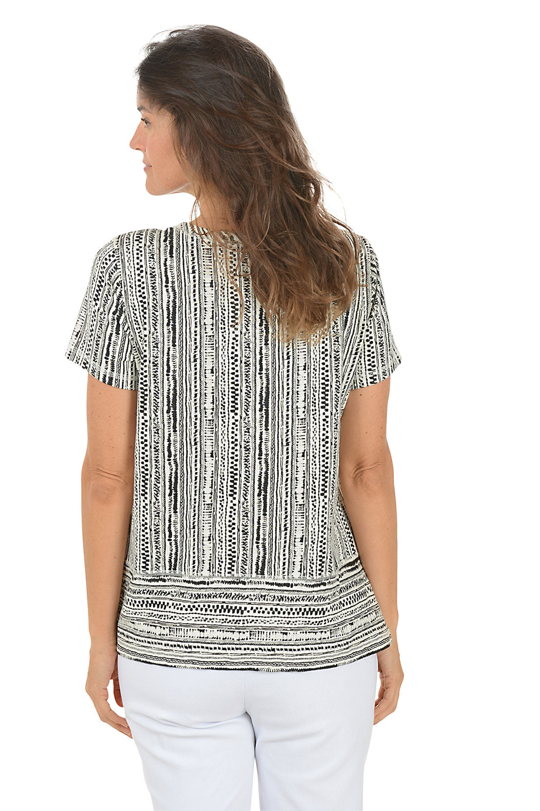 Woman wearing a patterned top and white pants on a white background. Back shot.