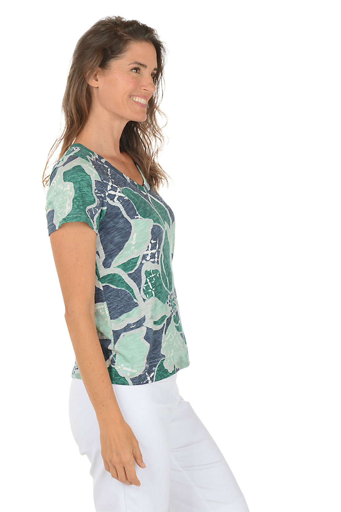 Woman wearing a patterned shirt with a white background. Side shot.