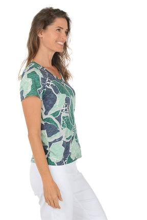 Woman wearing a patterned shirt with a white background. Side shot.