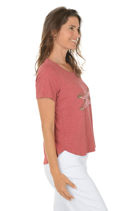 Woman wearing a red t-shirt with a dragonfly design on a white background. Side shot.