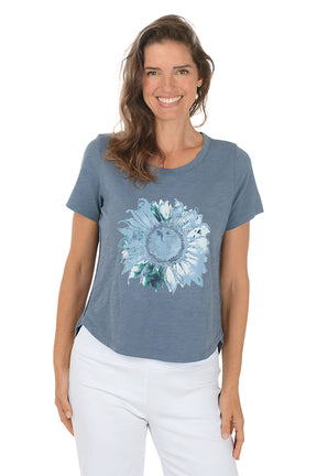 Woman wearing a blue t-shirt with a floral design on a white background. Second front shot.