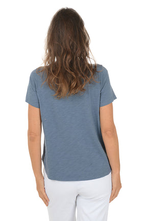 Woman wearing a blue t-shirt with a floral design on a white background. Back shot.