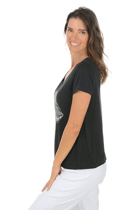 Woman wearing a black t-shirt with a floral design on a white background. Side shot.