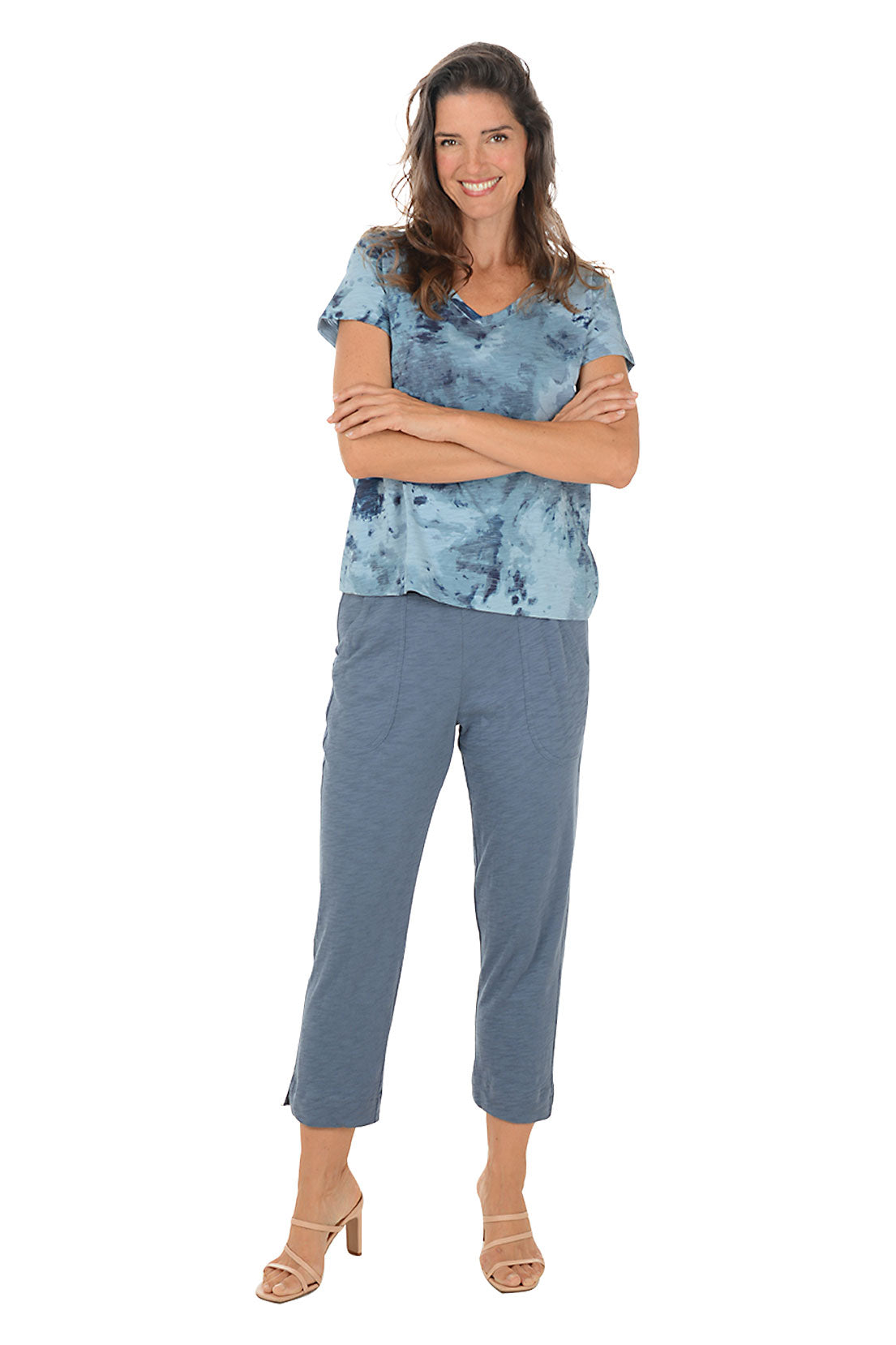 Woman wearing a blue patterned top and pants on a white background.
