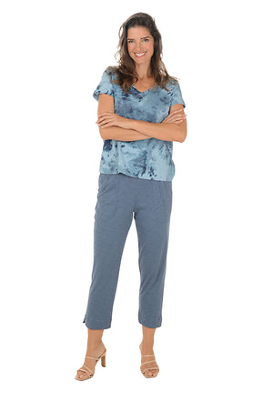 Woman wearing a blue patterned top and pants on a white background.
