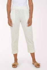 A model wearing a pair of light cream cropped pants with a textured heathered pattern, paired with a white top and tan slide sandals, set against a plain light background.