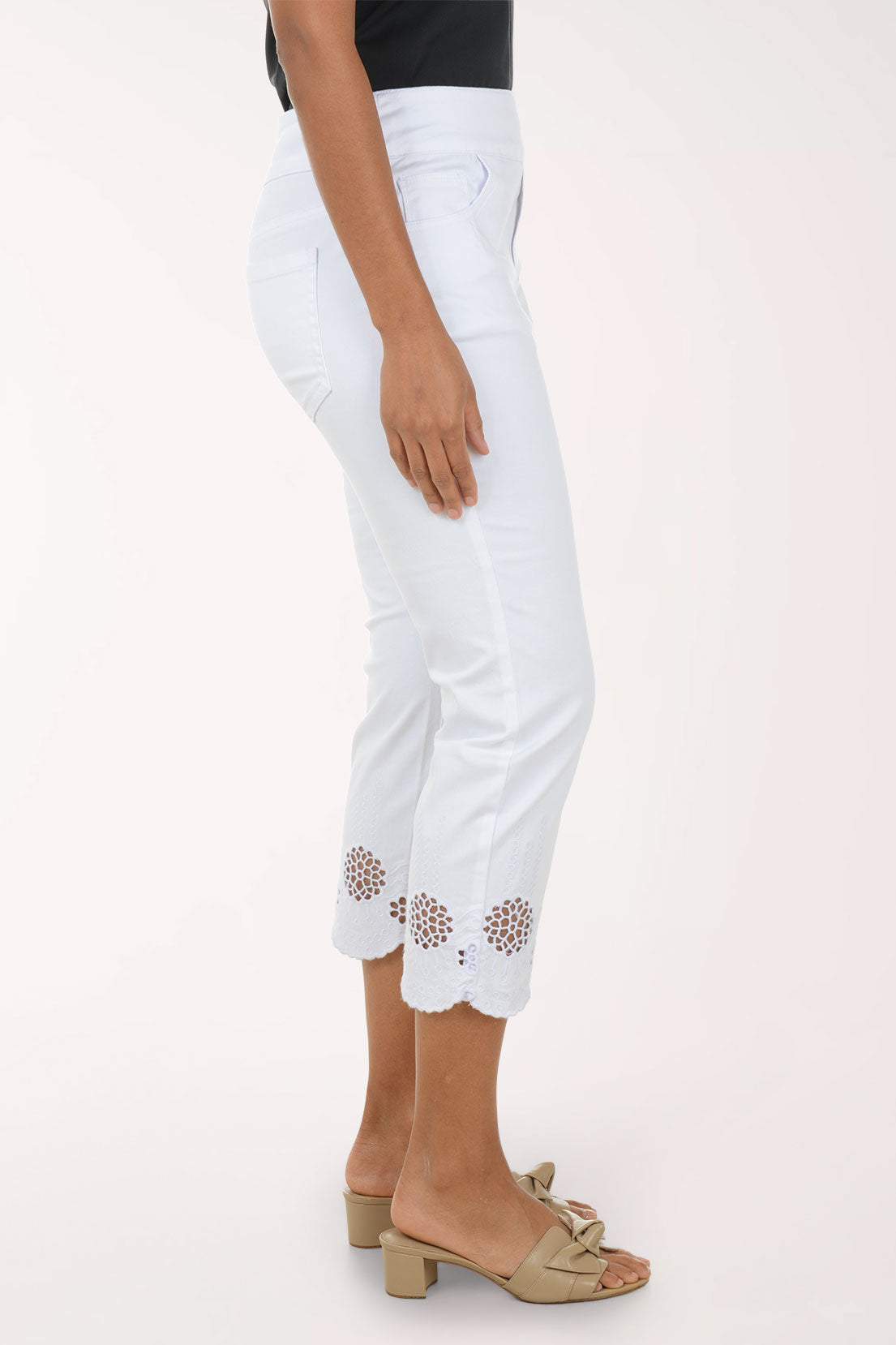 Woman wearing a blue embroidered top and white pants on a white background