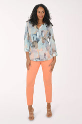 Woman wearing a patterned blouse and orange pants on a white background