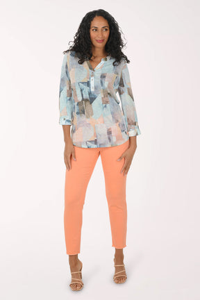 Woman wearing a patterned blouse and orange pants on a white background