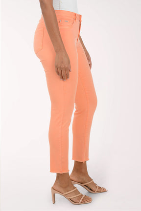 Woman wearing a patterned blouse and orange pants on a white background