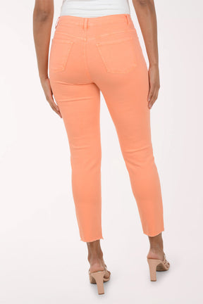 Woman wearing a patterned blouse and orange pants on a white background