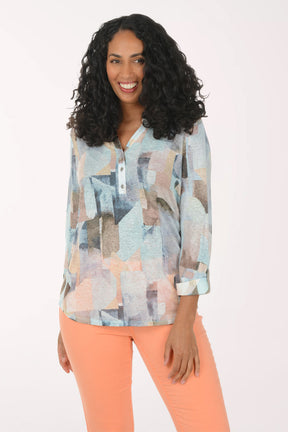 Woman wearing a patterned blouse and orange pants on a white background
