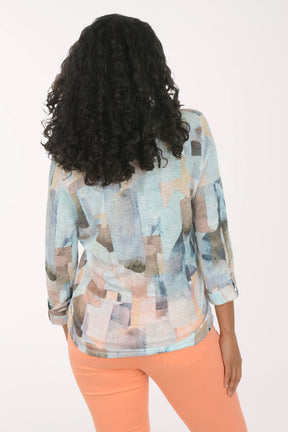 Woman wearing a patterned blouse and orange pants on a white background