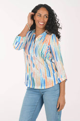 Woman wearing a colorful striped shirt and blue jeans on a white background
