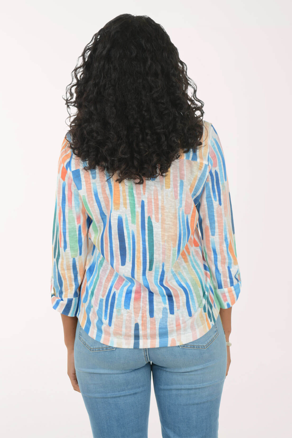 Person wearing a colorful striped shirt and blue jeans on a white background