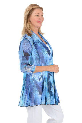 Woman wearing a blue patterned cardigan on a white background. Side shot.
