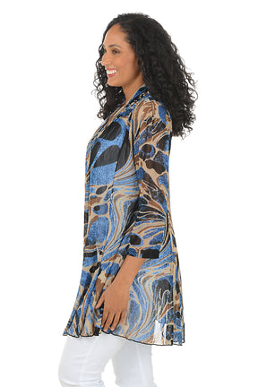 Woman wearing a patterned cardigan over a white top and pants on a white background. Side shot.