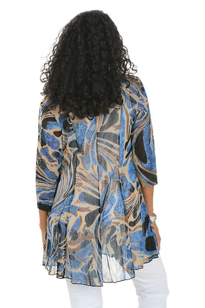 Woman wearing a patterned cardigan over a white top and pants on a white background. Back shot.