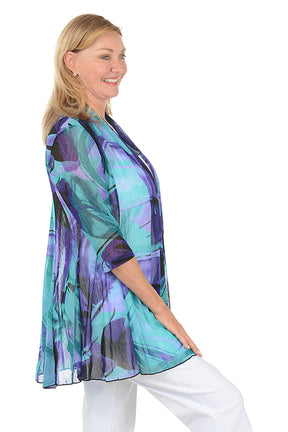 Woman wearing a colorful cardigan with a white background. Side shot.