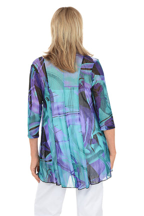 Woman wearing a colorful cardigan with a white background. Back shot.