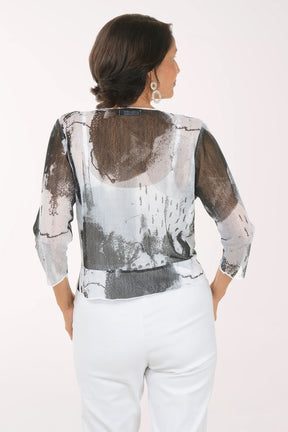 Woman wearing a patterned cardigan over a white top and pants on a white background