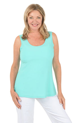 Woman wearing a light blue sleeveless top and white pants on a white background.