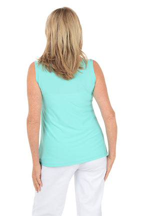 Woman wearing a light blue sleeveless top and white pants on a white background. Back shot.