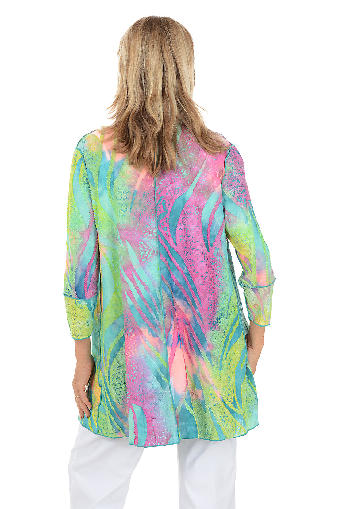 Woman wearing a colorful, patterned shirt with a white background. Back shot.