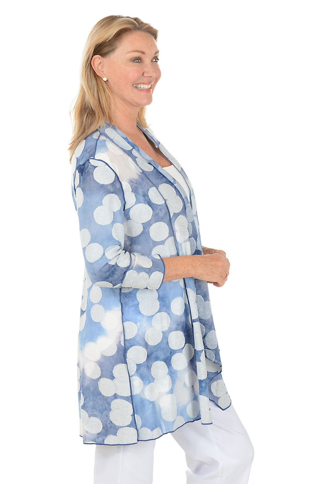 Woman wearing a blue and white patterned cardigan on a white background. Side shot.