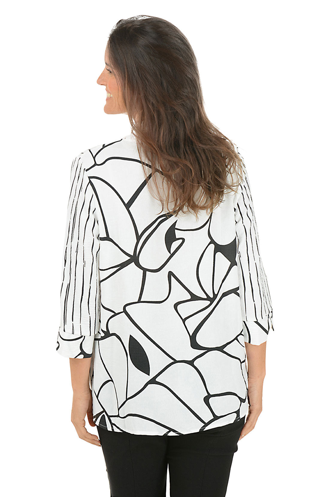 Woman wearing a black and white patterned blouse on a white background. Back shot.