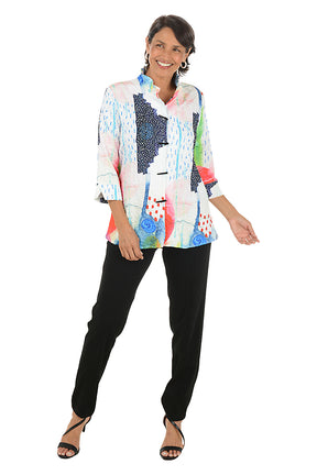Woman wearing a colorful patterned blouse and black pants on a white background