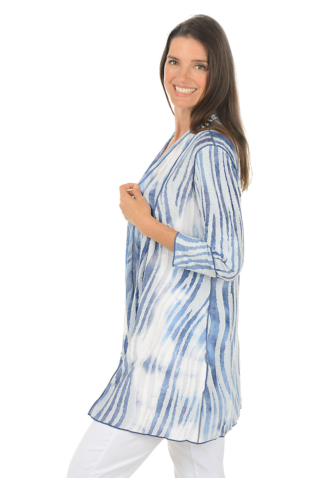 Woman wearing a blue and white tie-dye shirt on a white background. Side shot.