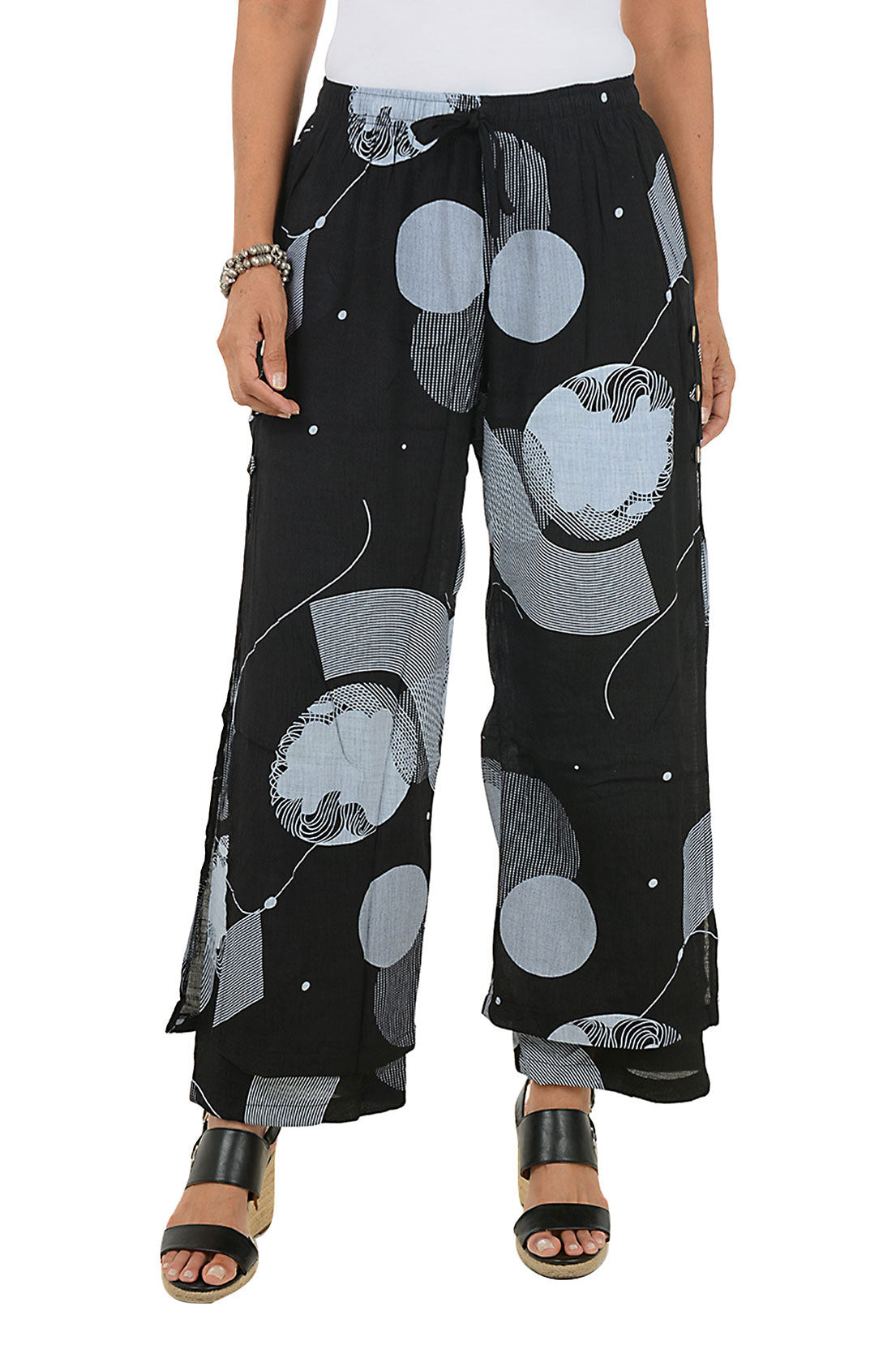 Black pants with gray circle pattern worn by a person on a white background.