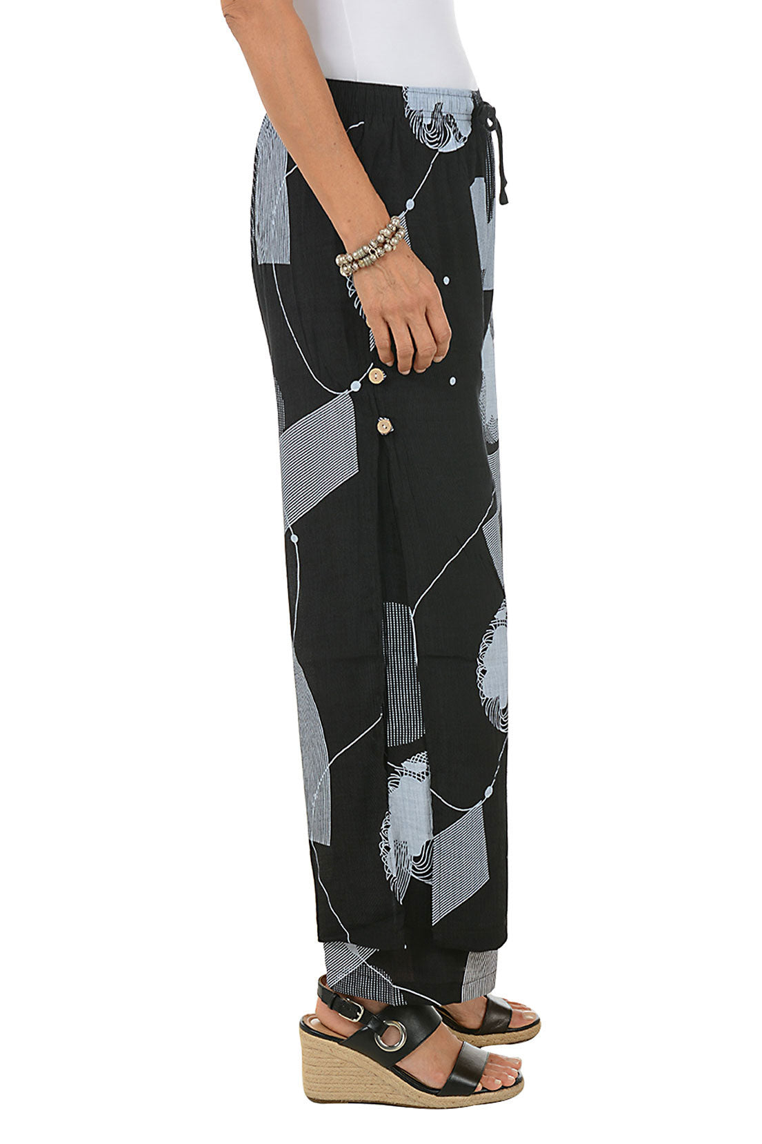 Black pants with gray circle pattern worn by a person on a white background. Side shot.